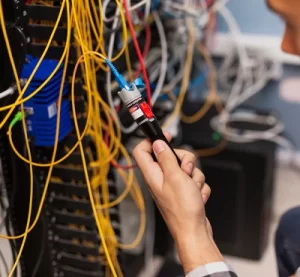 Técnico utilizando un localizador visual de fallas (VFL) para verificar la continuidad de un cable de fibra óptica en un rack.